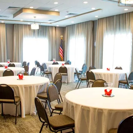 Espacio representativo del hotel: Una sala de reuniones luminosa con mesas redondas y sillas.