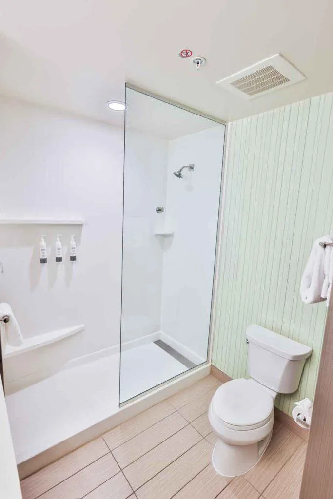 Espacio representativo del hotel: Un baño luminoso con ducha de vidrio e inodoro.