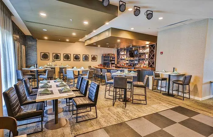 Espacio representativo del hotel: Un comedor de restaurante con mesas, asientos y una barra.