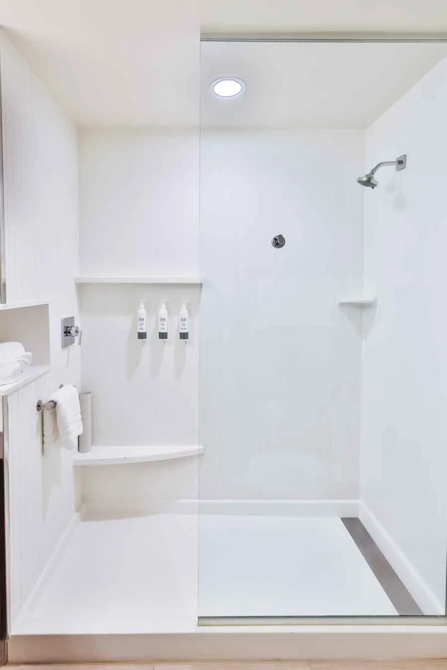 Espacio representativo del hotel: Un baño luminoso con ducha y estantes empotrados en la pared.