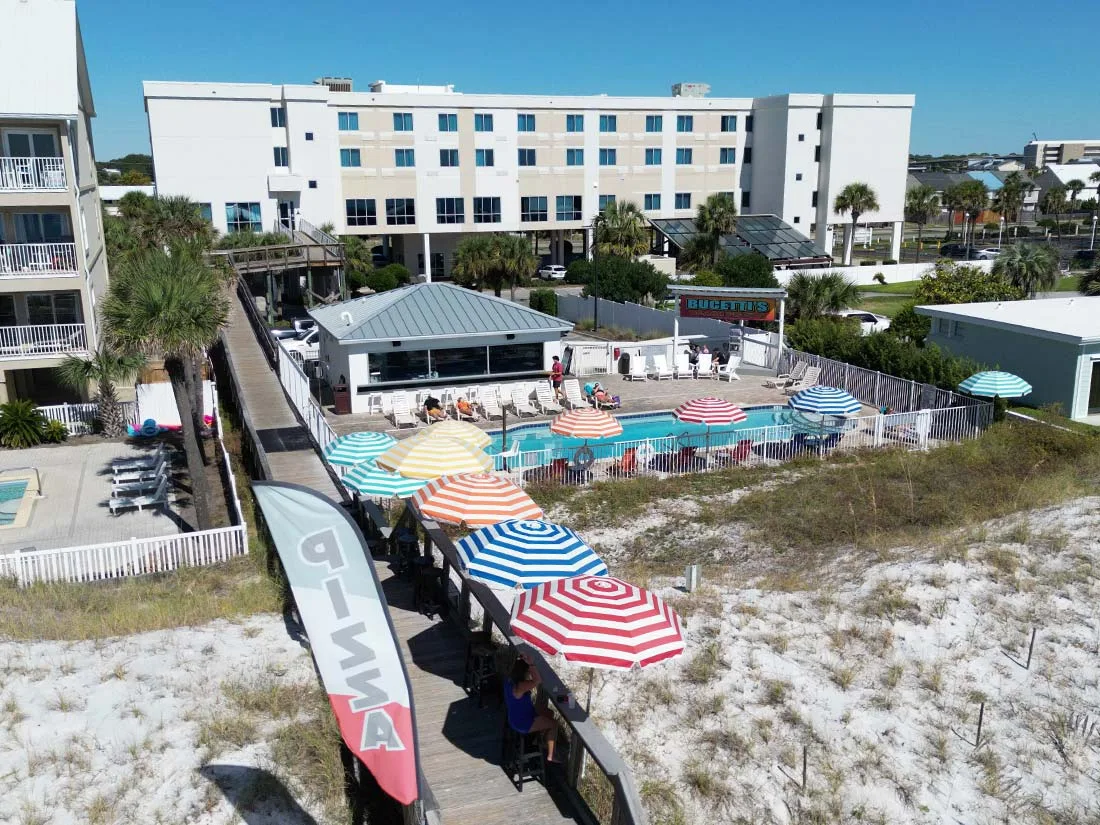 Espacio representativo del hotel: Una piscina al aire libre y sombrillas coloridas están junto a un hotel cerca de la playa.