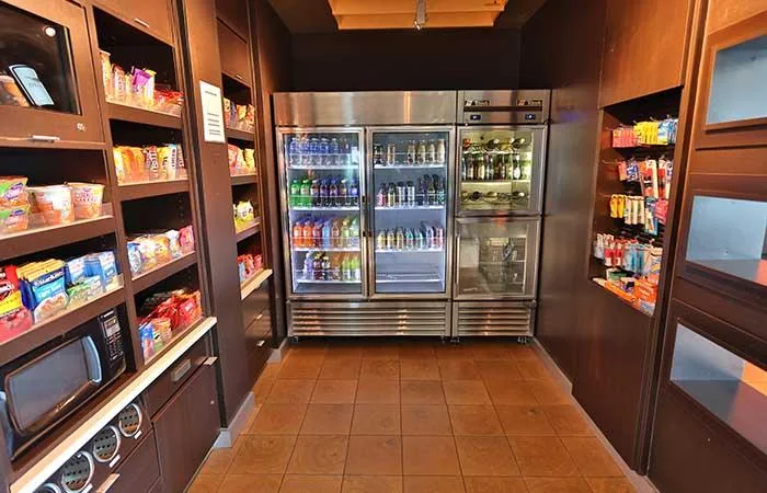 Espacio representativo del hotel: Área de refrigerios de hotel con estantes de alimentos envasados y bebidas refrigeradas.