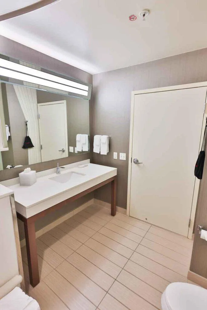 Espacio representativo del hotel: Un baño con un tocador largo, lavabo y espejo grande.