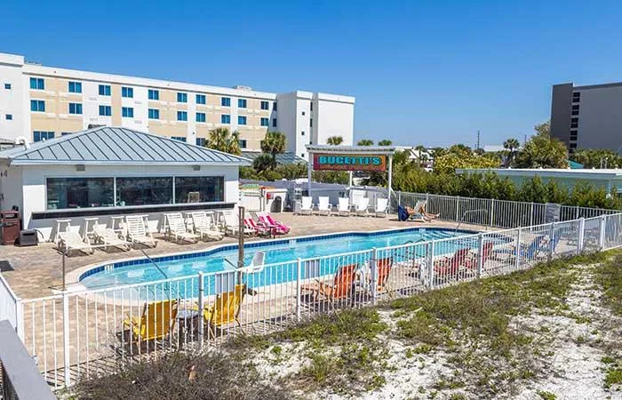 Espacio representativo del hotel: Una piscina al aire libre está junto a un edificio hotelero y un patio cercado.