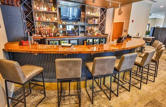 Espacio representativo del hotel: Una barra con mostrador curvo de madera y taburetes tapizados.
