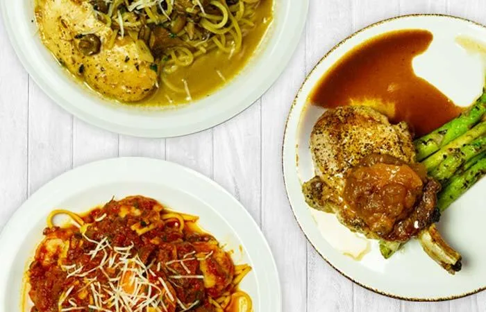 Espacio representativo del hotel: Platos de pasta y comida cocinada están dispuestos sobre una mesa clara.