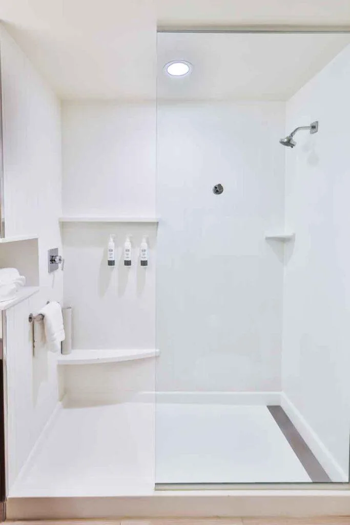 Espacio representativo del hotel: Baño luminoso con ducha y artículos de aseo colocados en la pared.