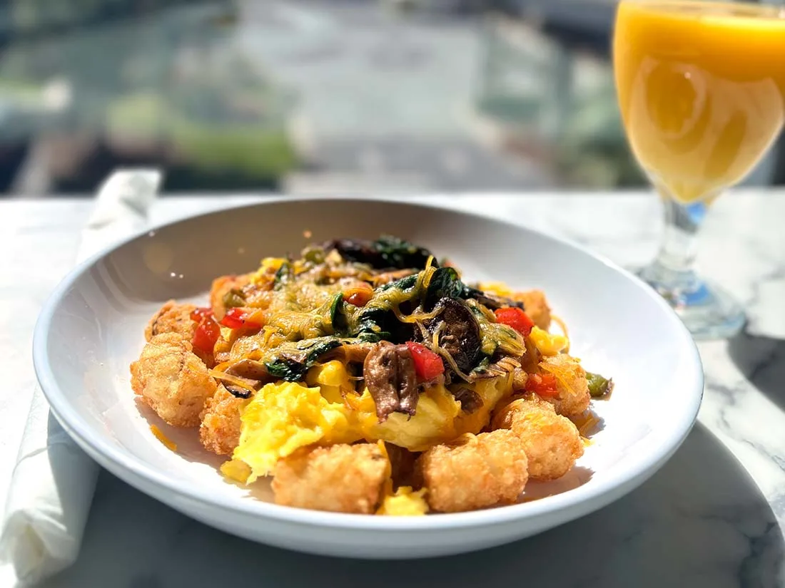 Espacio representativo del hotel: Un plato de comida con verduras y un vaso de zumo de naranja sobre una mesa.