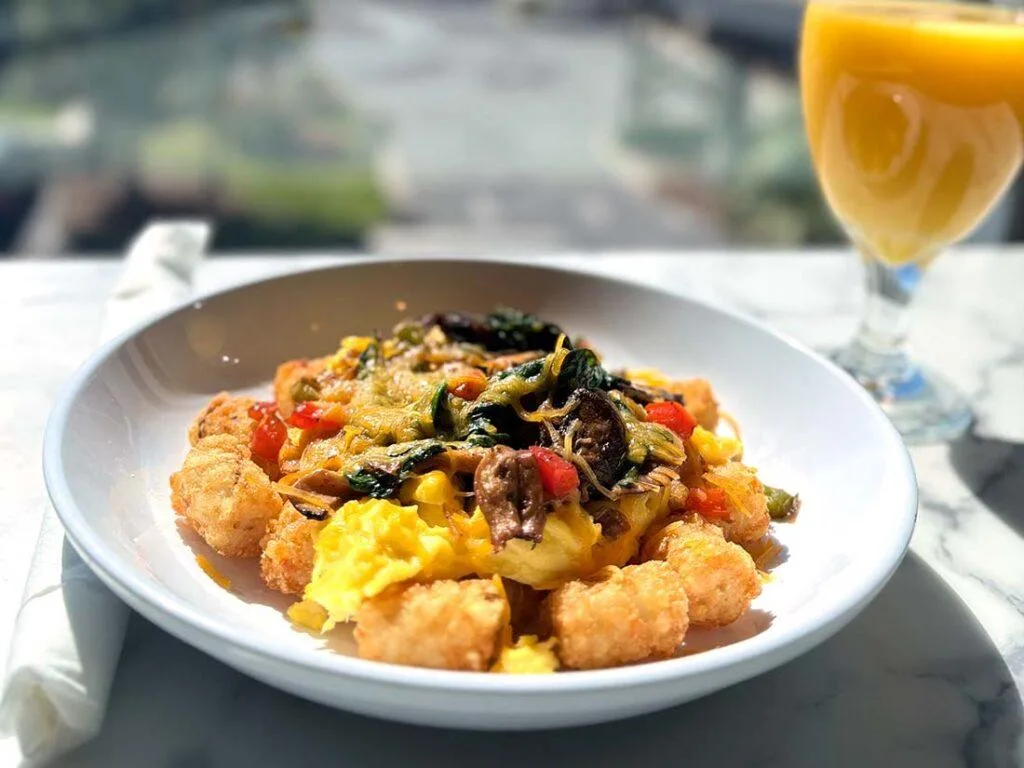 Espacio representativo del hotel: Un plato con huevos revueltos y verduras está junto a un vaso de jugo de naranja.
