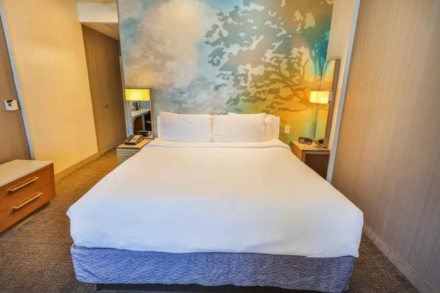 Espacio representativo del hotel: Un dormitorio con una cama grande, mesitas de noche y decoración mural estampada.