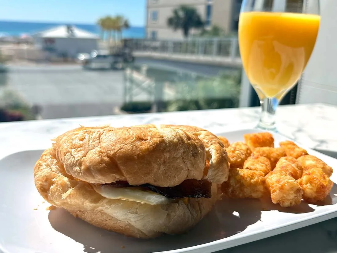 Espacio representativo del hotel: Un sándwich de desayuno y patatas fritas están en un plato junto a un vaso de zumo de naranja.