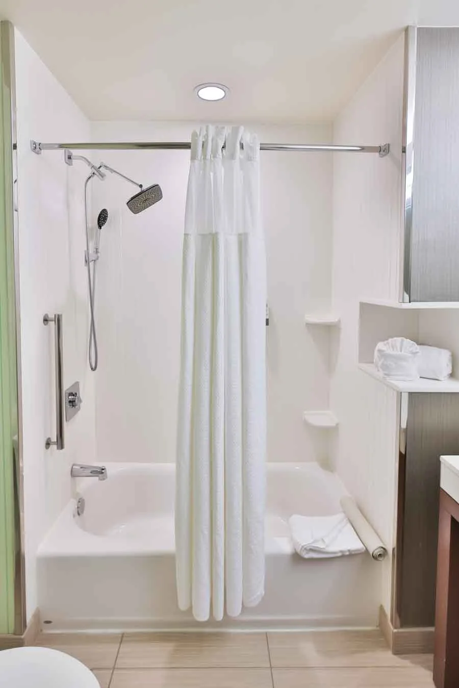 Espacio representativo del hotel: Un baño con ducha y bañera, cortina blanca y toallas dobladas.