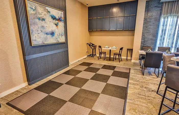 Espacio representativo del hotel: Un salón de hotel con mesas, asientos y una gran obra abstracta.