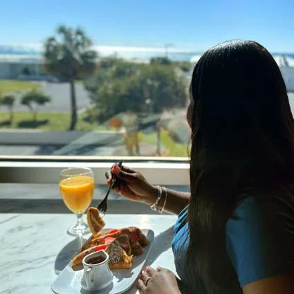 Espacio representativo del hotel: Una persona desayuna junto a una ventana con vistas a un paisaje verde.