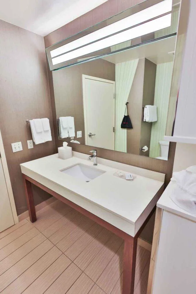 Espacio representativo del hotel: Un lavabo de baño con un espejo amplio y toallas dobladas.