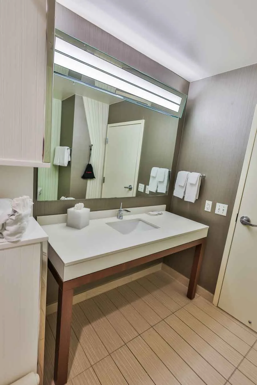 Espacio representativo del hotel: Un tocador de baño con un espejo grande y un lavabo sobre la encimera.