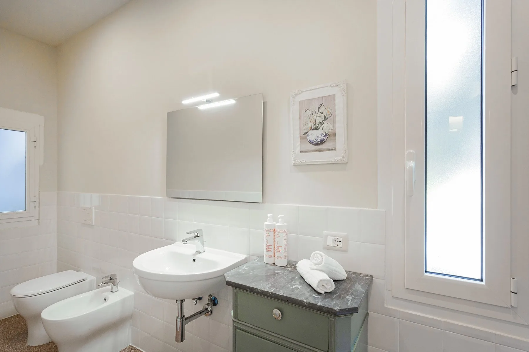 Bathroom with a sink, bidet, and a window.