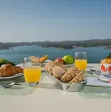 Espacio representativo del hotel: Una mesa de desayuno junto al mar tiene vistas al agua y a colinas lejanas.