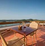 Espacio representativo del hotel: Una zona de comedor en una terraza con mesa y sillas da al agua.