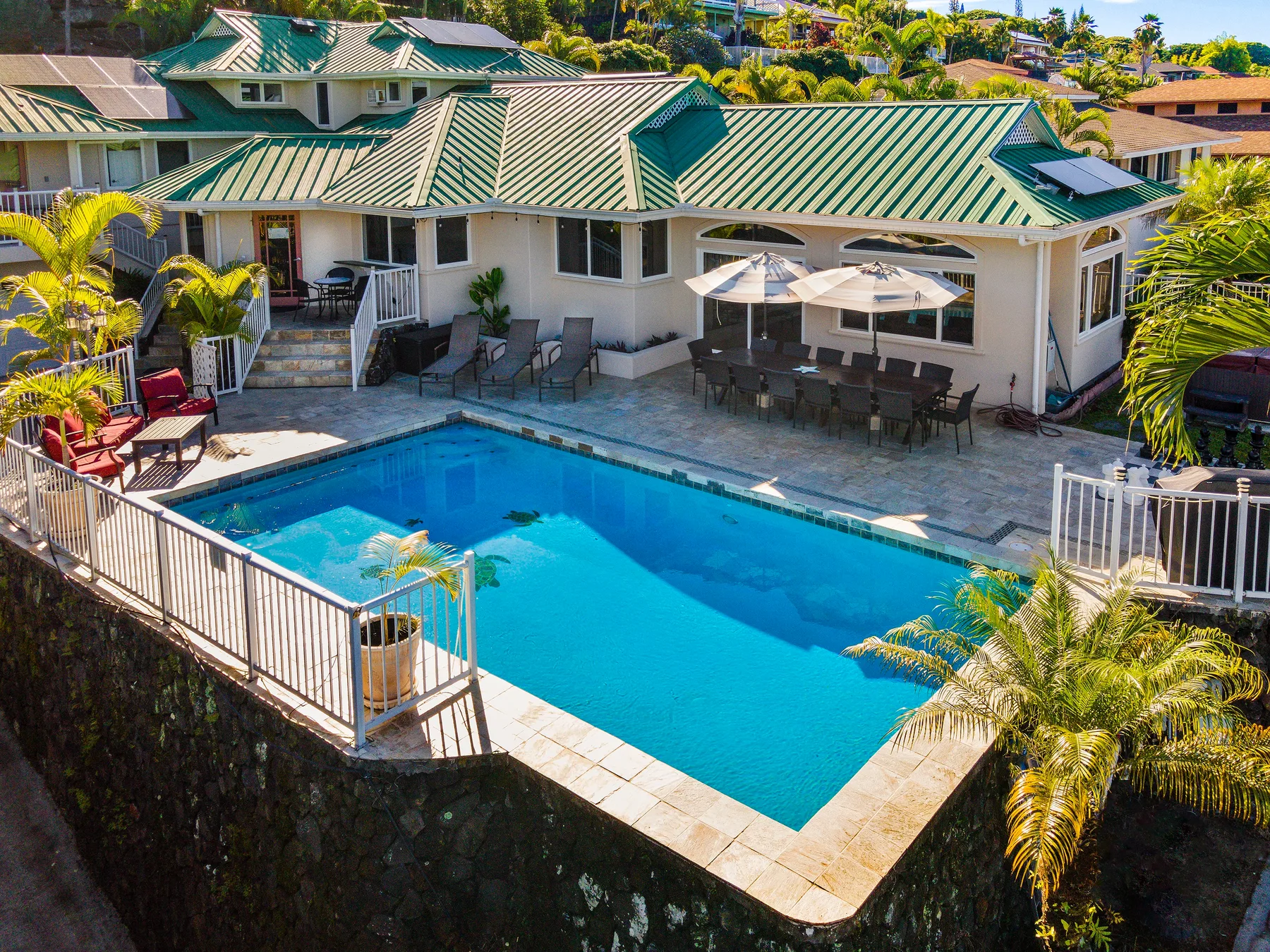 A swimming pool beside a building with outdoor seating and umbrellas.