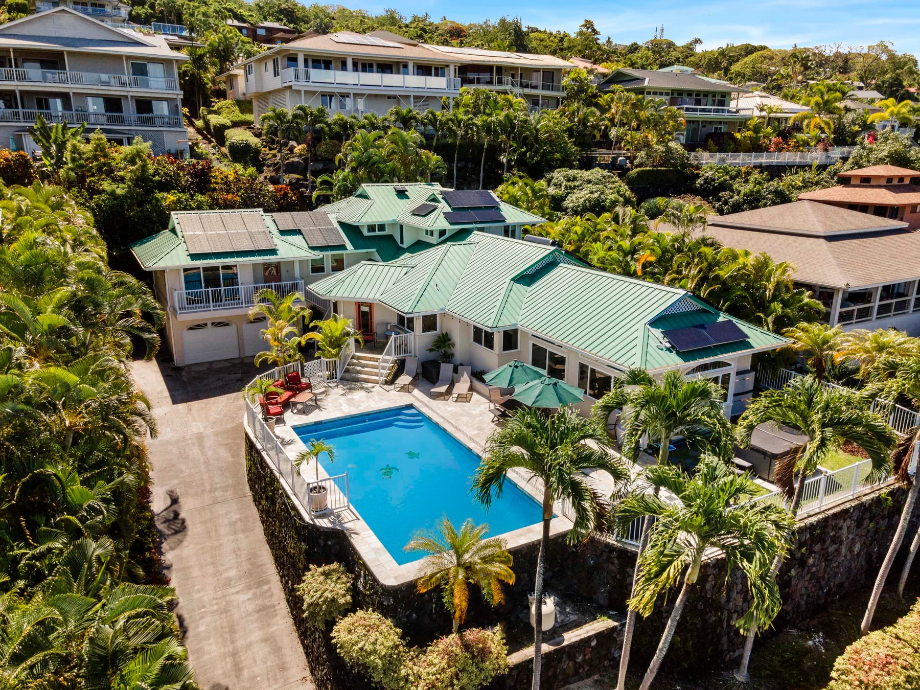 Aerial view of a tropical residence with a swimming pool and surrounding greenery.