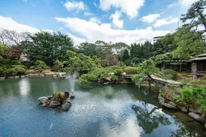 Espacio representativo del hotel: Un jardín ajardinado rodea un estanque con rocas y árboles.