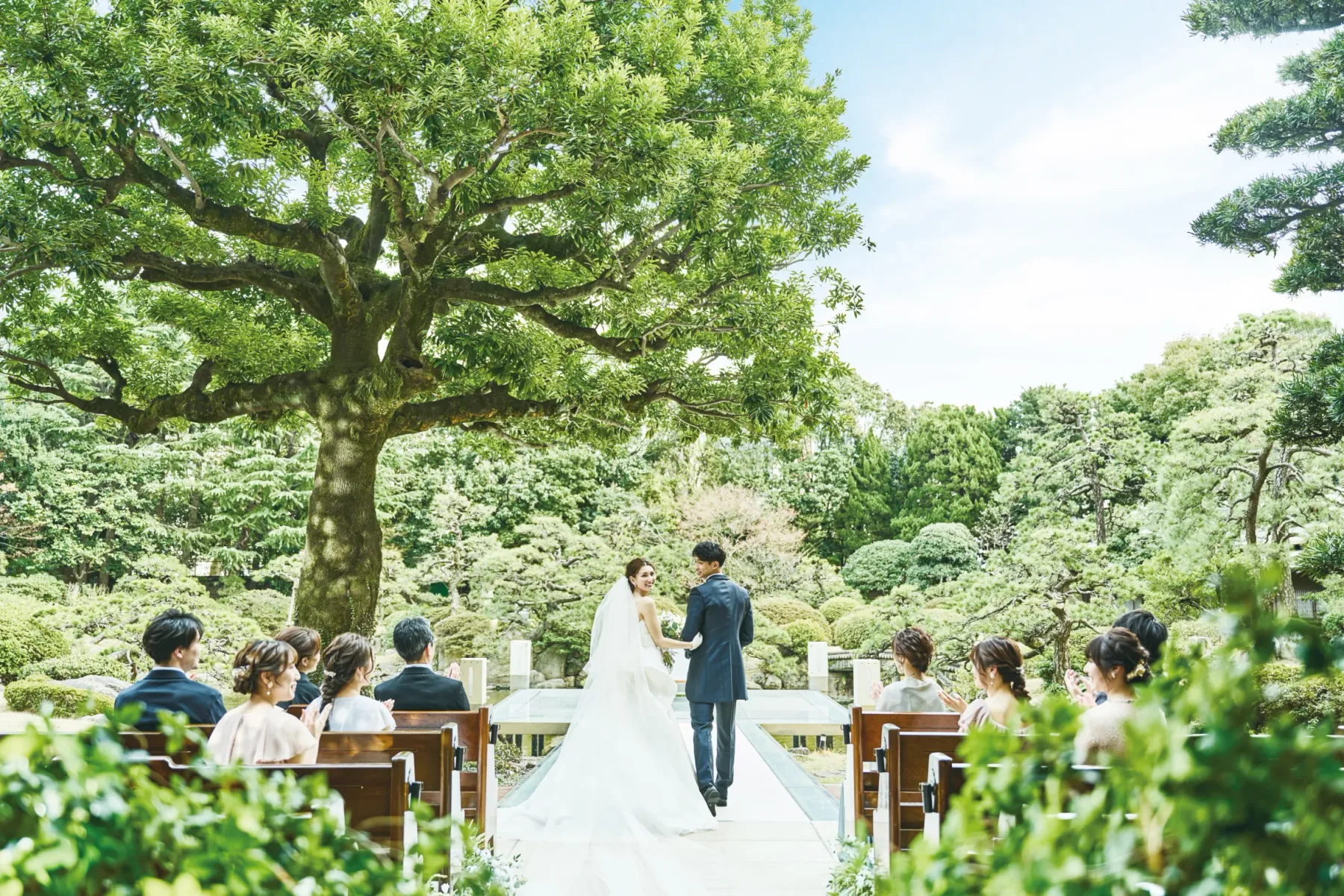 Espacio representativo del hotel: Una ceremonia de boda se celebra en un jardín bajo un árbol grande.