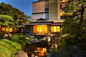 Espacio representativo del hotel: Un edificio de hotel da a un estanque ajardinado con ventanas iluminadas.