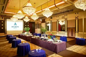 Espacio representativo del hotel: Un salón de banquetes con mesas, manteles azules y lámparas de araña.