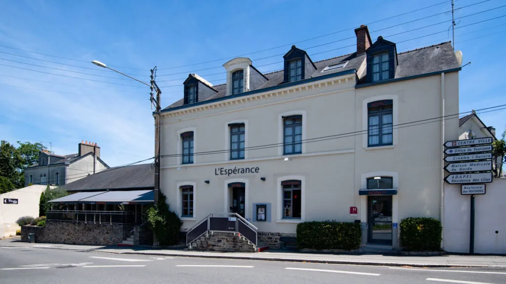 Representative hotel space: A white hotel building with dark roof windows faces a street.
