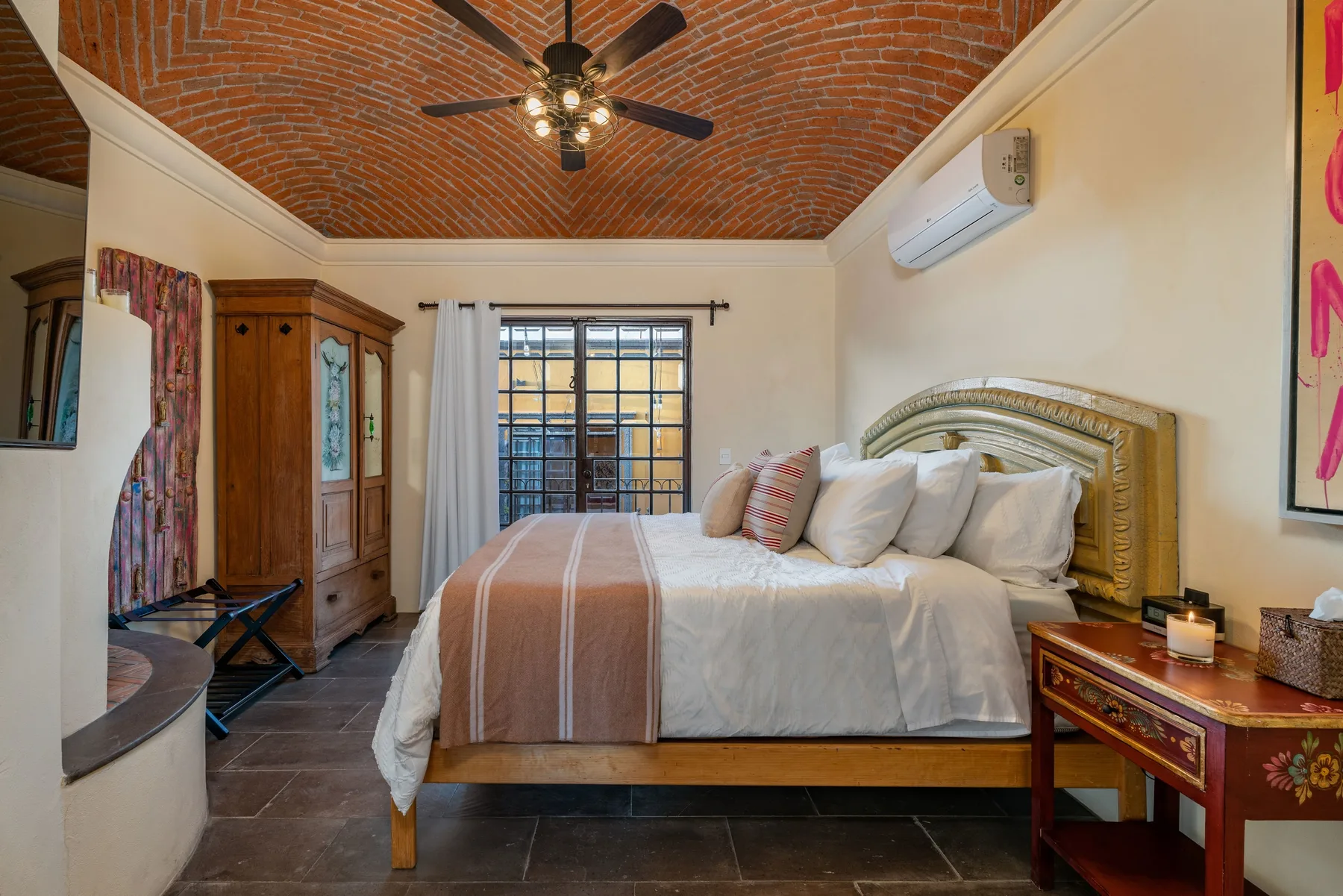 A bedroom with a large bed beneath a brick vaulted ceiling.
