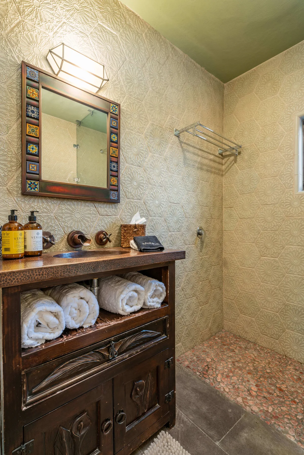 A tiled bathroom with a vanity, mirror, and folded towels.