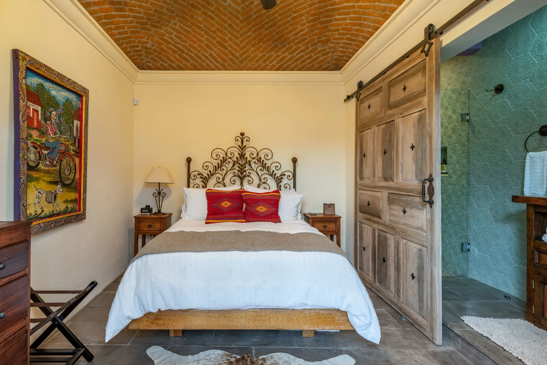A bedroom with a bed beneath a decorative metal headboard.