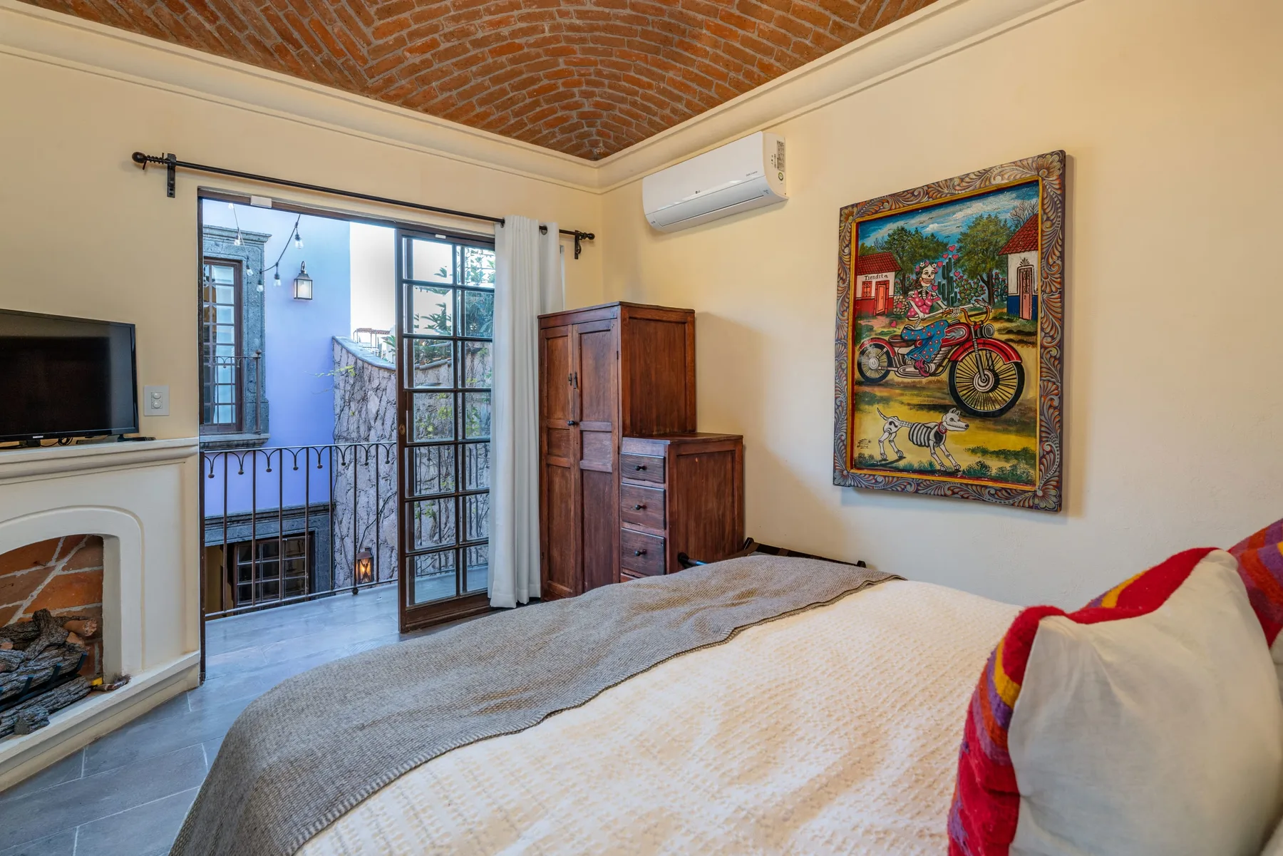 A bedroom with a bed, a glass door, and colorful artwork on the wall.
