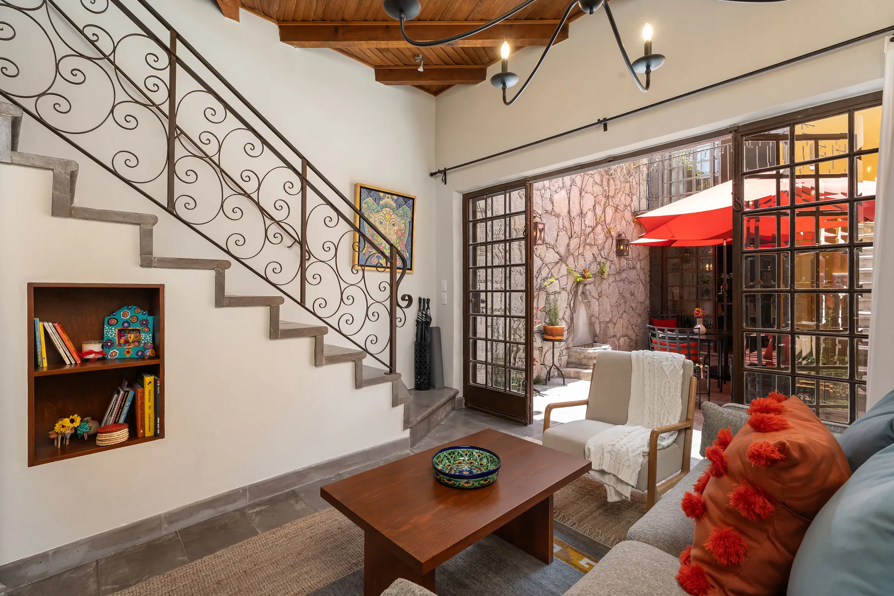 A living room with a staircase, seating, and large glass doors opening to a patio.