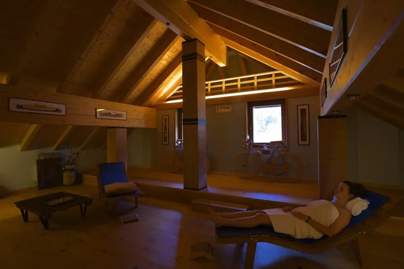 Representative hotel space: A dim attic lounge has exposed wooden beams, seating, and a small table.