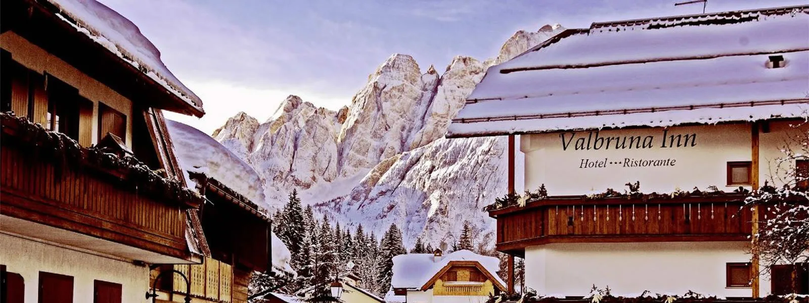 Representative hotel space: A mountain inn stands among snowy peaks and pine trees.
