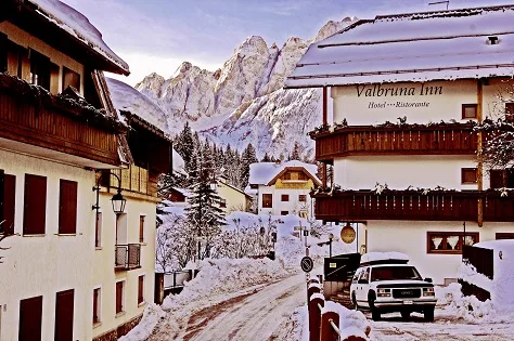 Representative hotel space: Snowy mountain village street with alpine buildings and a parked vehicle.