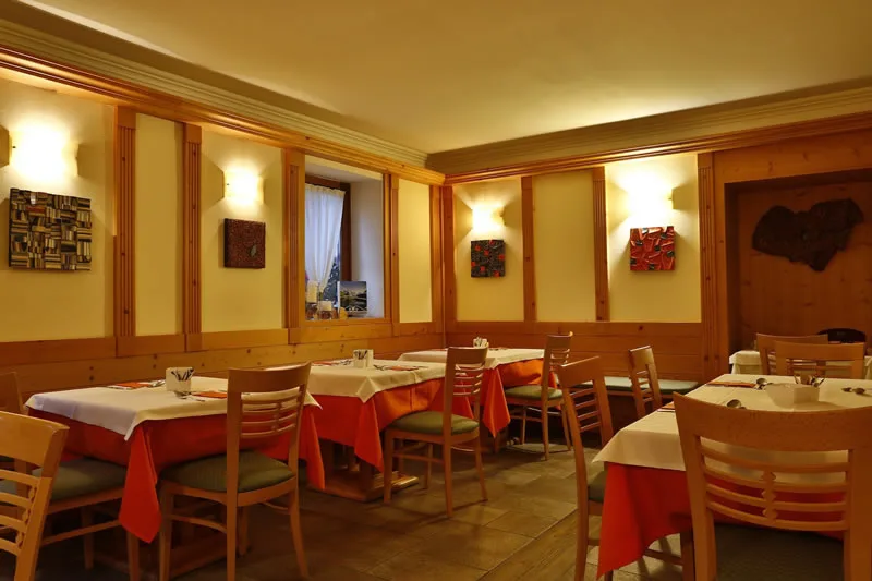 Representative hotel space: A warmly lit dining room with wooden tables and red tablecloths.