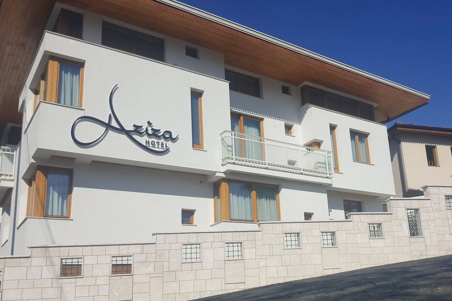 Representative hotel space: Hotel exterior with balconies and a stone boundary wall.