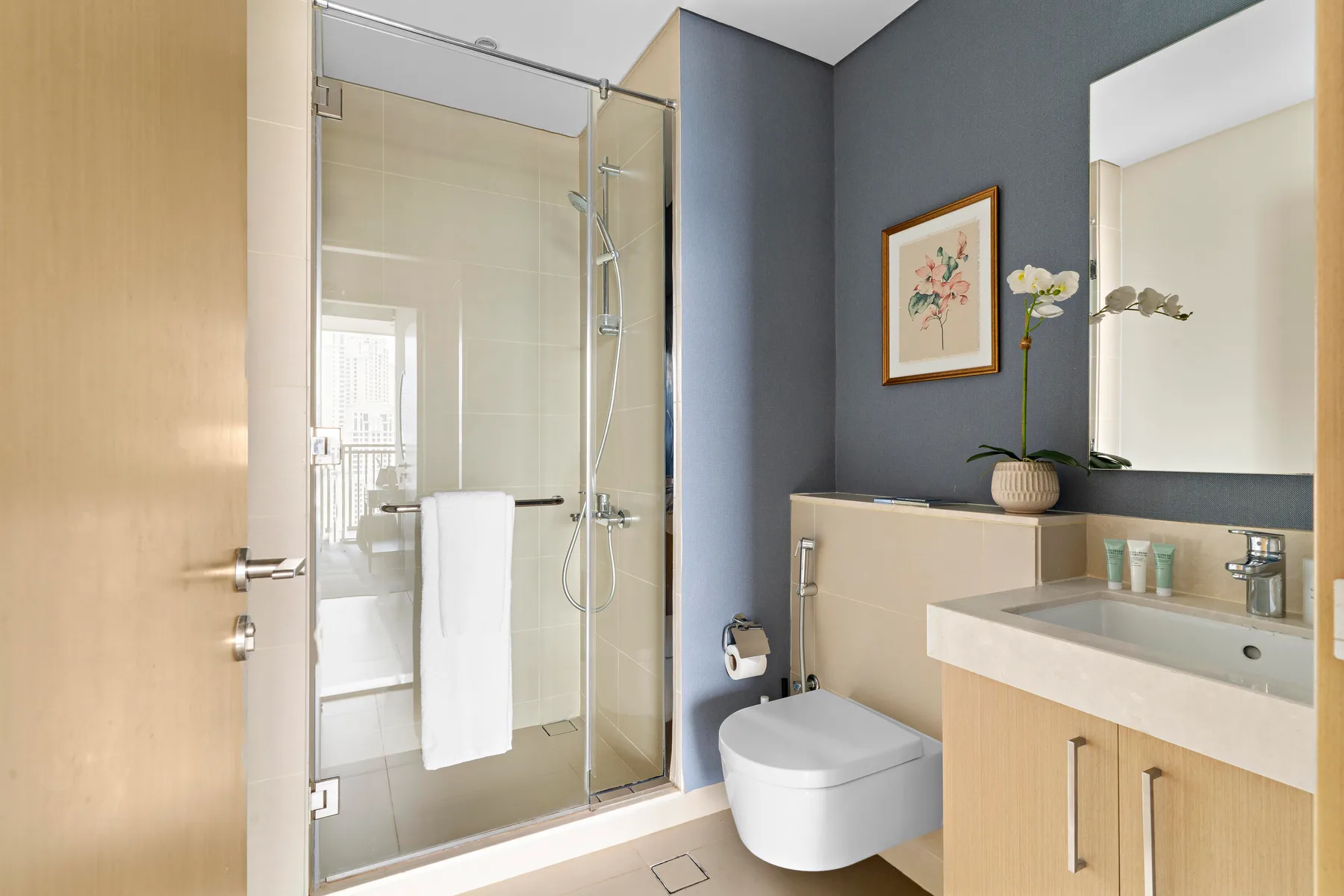 Un baño moderno con ducha de vidrio, inodoro suspendido y lavabo.