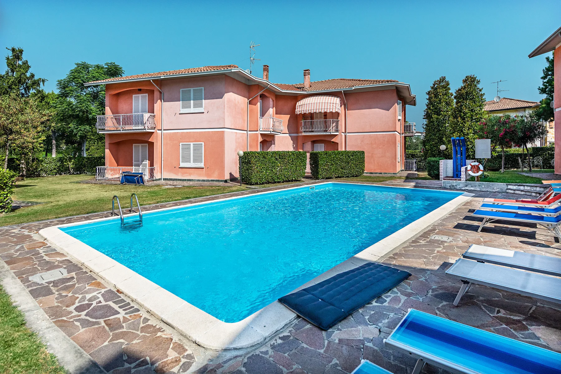 Shared amenity: An outdoor swimming pool sits beside a pink multi-story building.