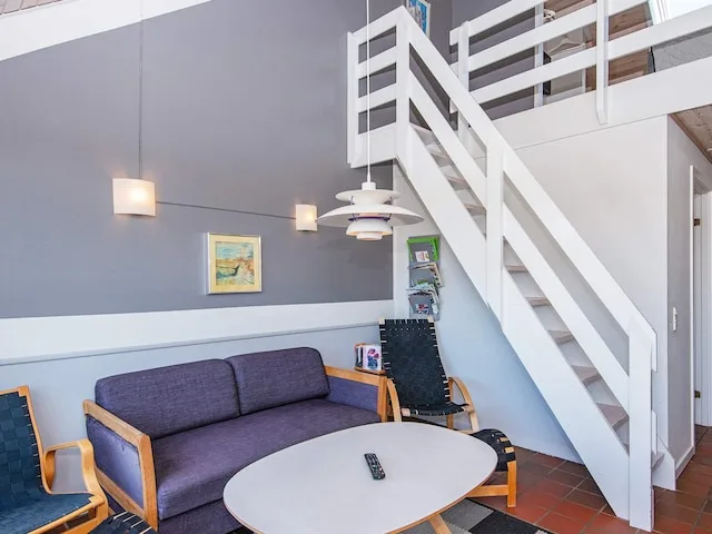 A living area with purple seating and a white staircase leading to an upper level.
