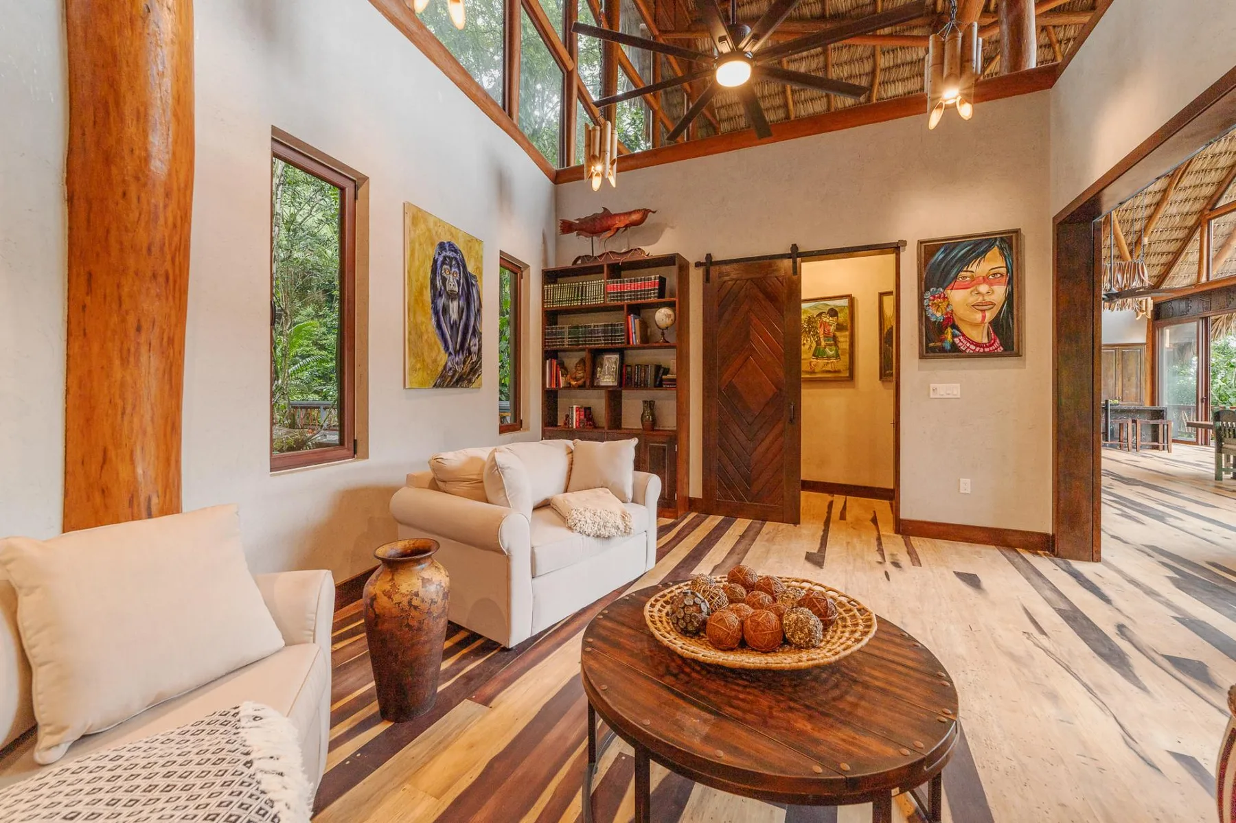A bright living room with seating, a round wooden table, and colorful artwork.