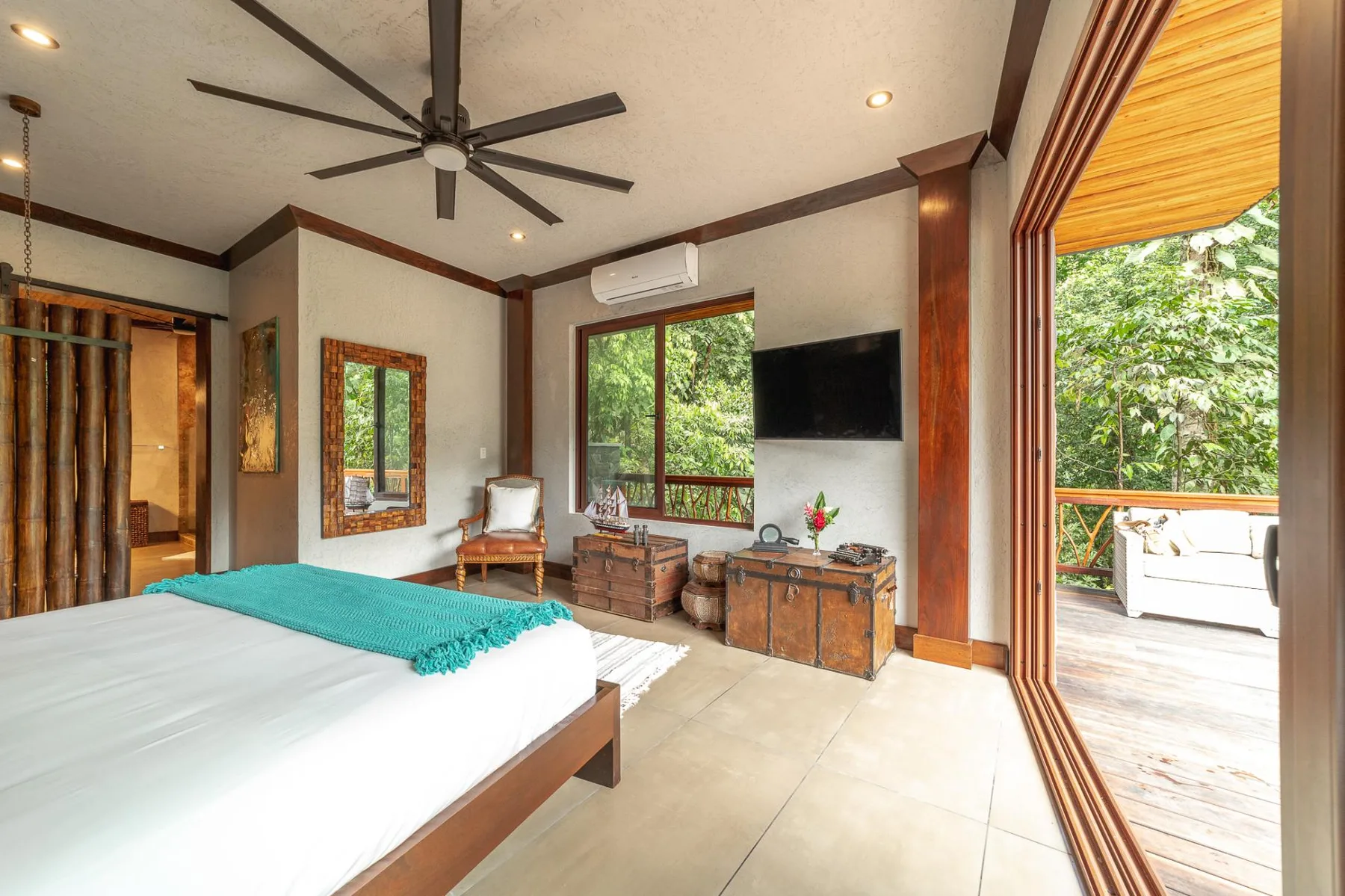 A bedroom with a bed, television, and wide glass doors opening onto a patio.