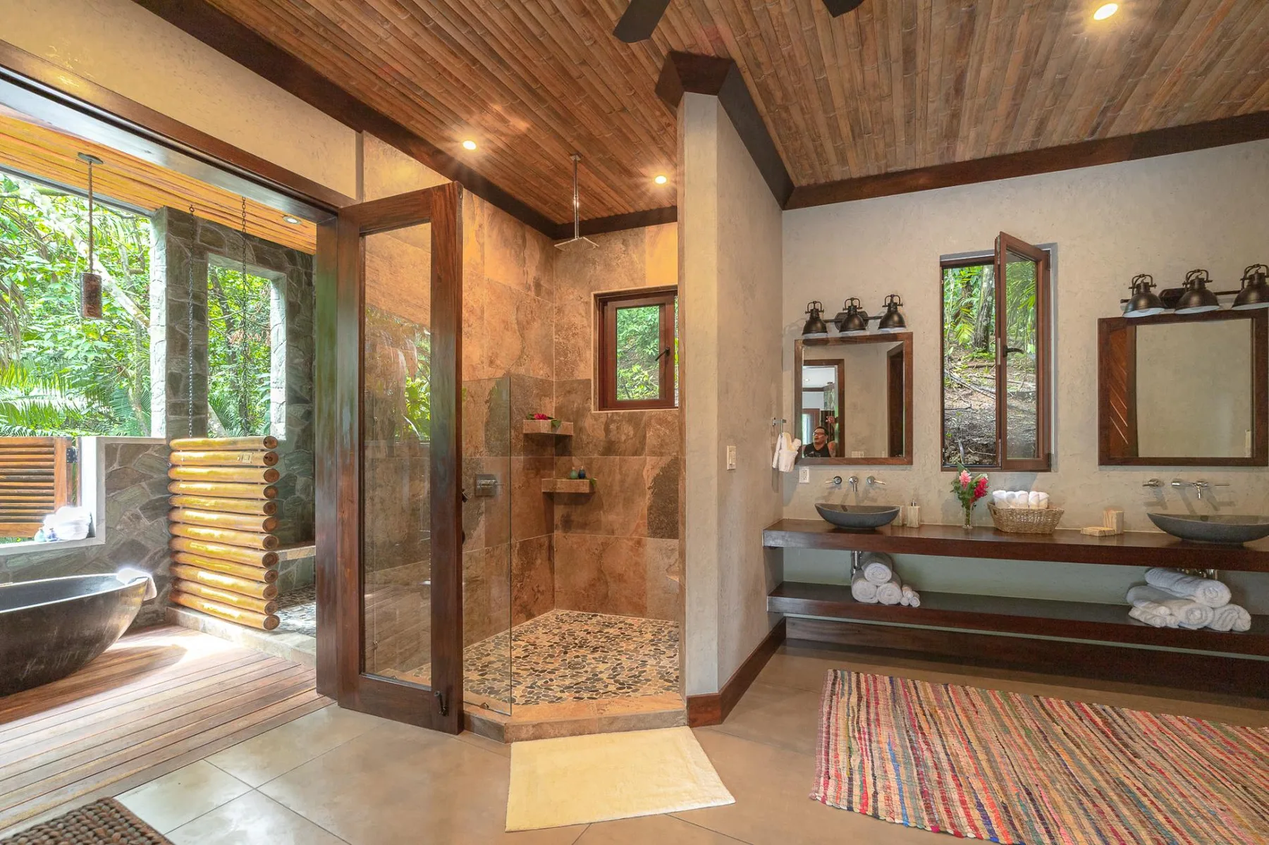 A spacious bathroom with a glass-enclosed shower, vanity sinks, and a freestanding tub.