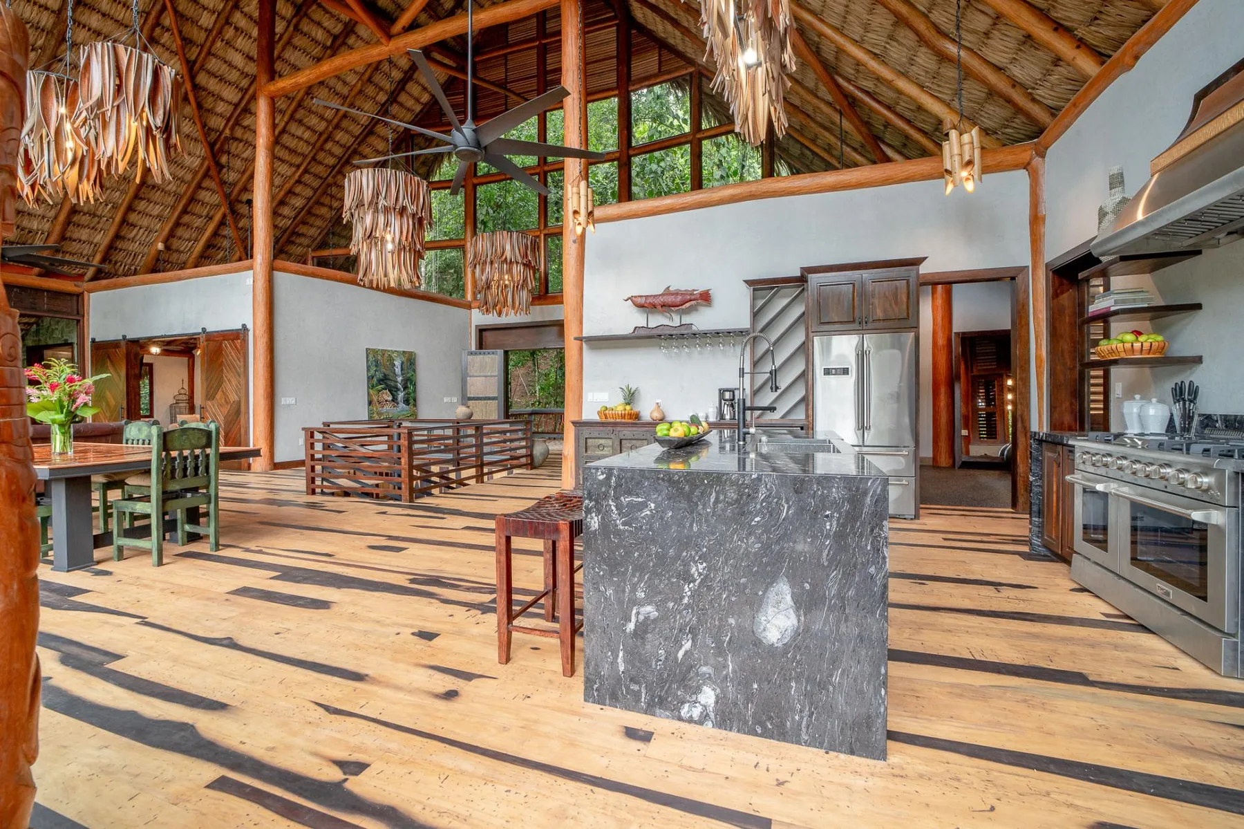A spacious kitchen and dining area with a central island and exposed timber ceiling.