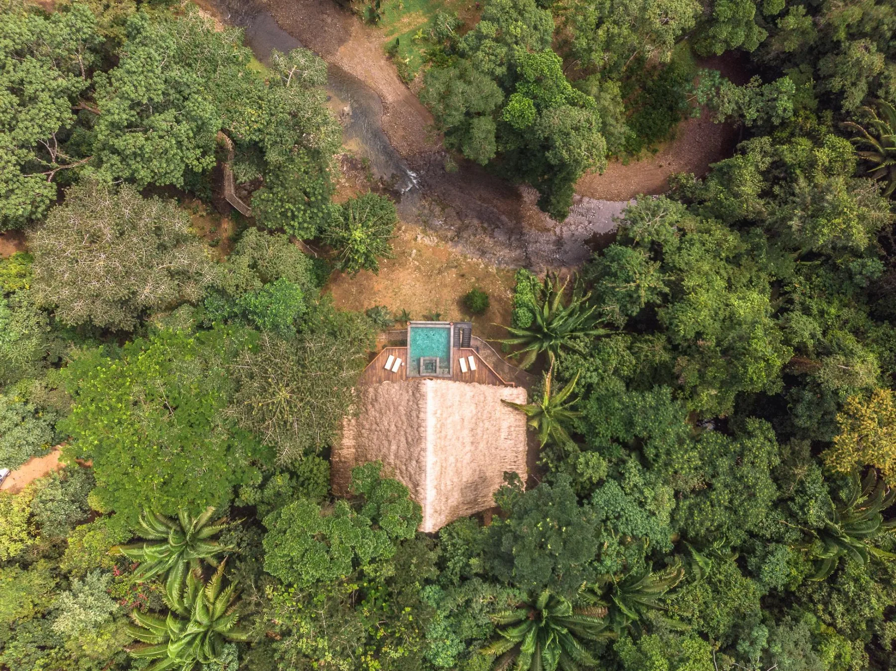 Aerial view of a small building surrounded by dense green trees.