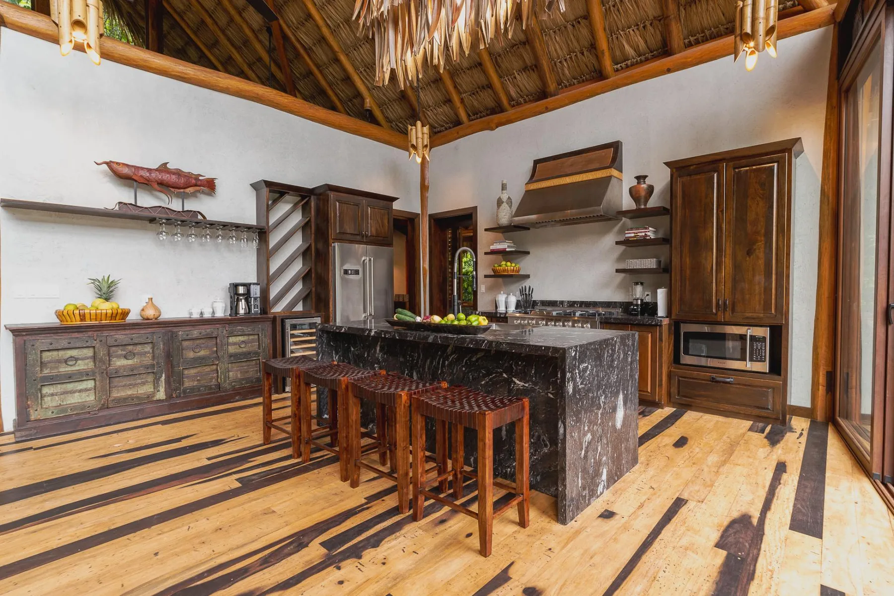 A kitchen with a dark central island and wooden bar stools.