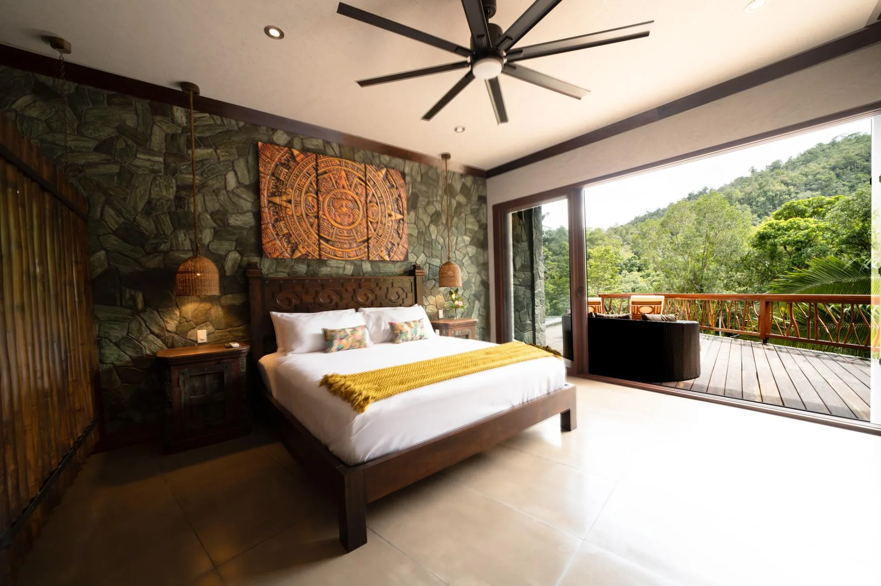 A bedroom with a bed beside open doors leading to a wooden deck.
